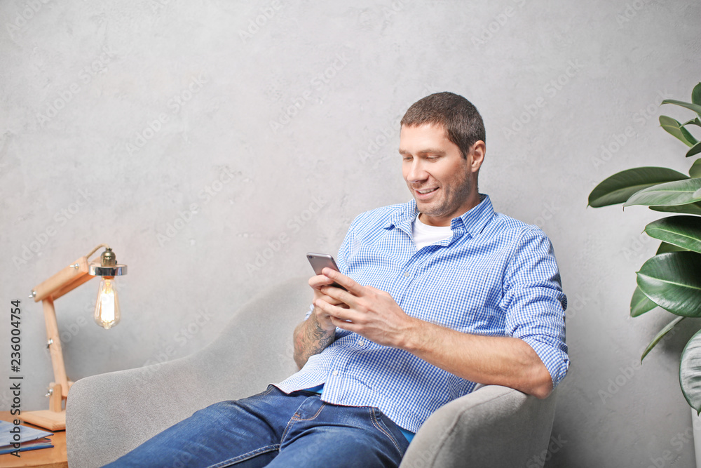 © Africa Studio - Young man in casual clothes using cell phone at home
