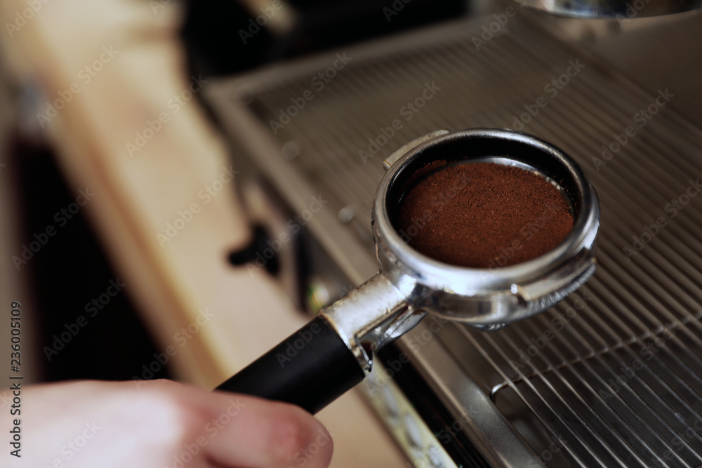 Barista holding portafilter with ground coffee, closeup. Space for text