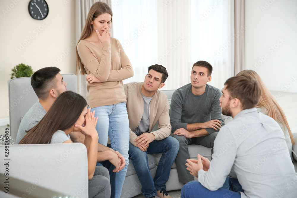 Young woman talking about her problems during group therapy Young woman talking about her problems during group therapy