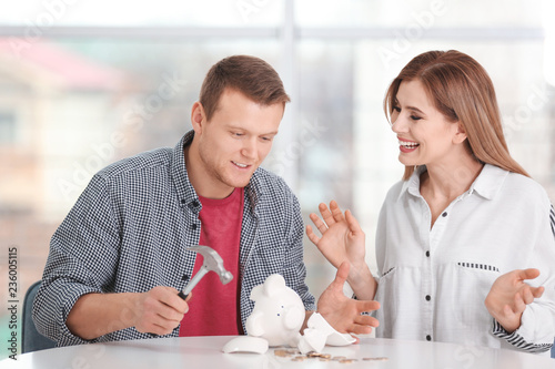 Young couple breaking piggy...