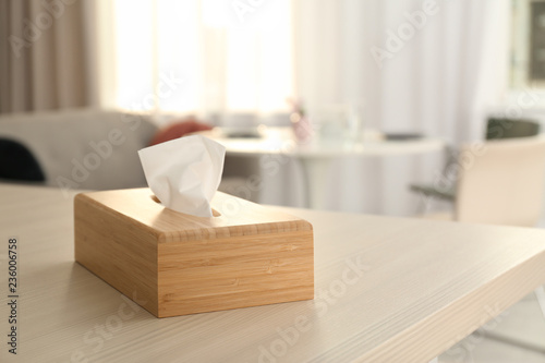 Wooden napkin holder with paper serviettes on table in room. Space for text