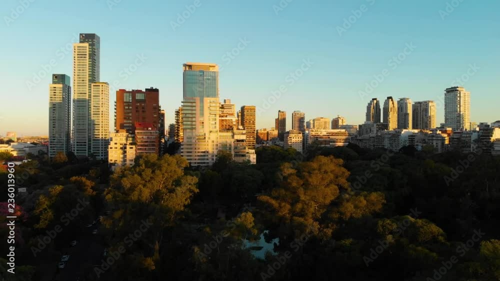 Wide Aerial drone view of Palermo Neighborhood in Buenos Aires during sunset with city park and skyscrapers buildings. Warm orange colors.