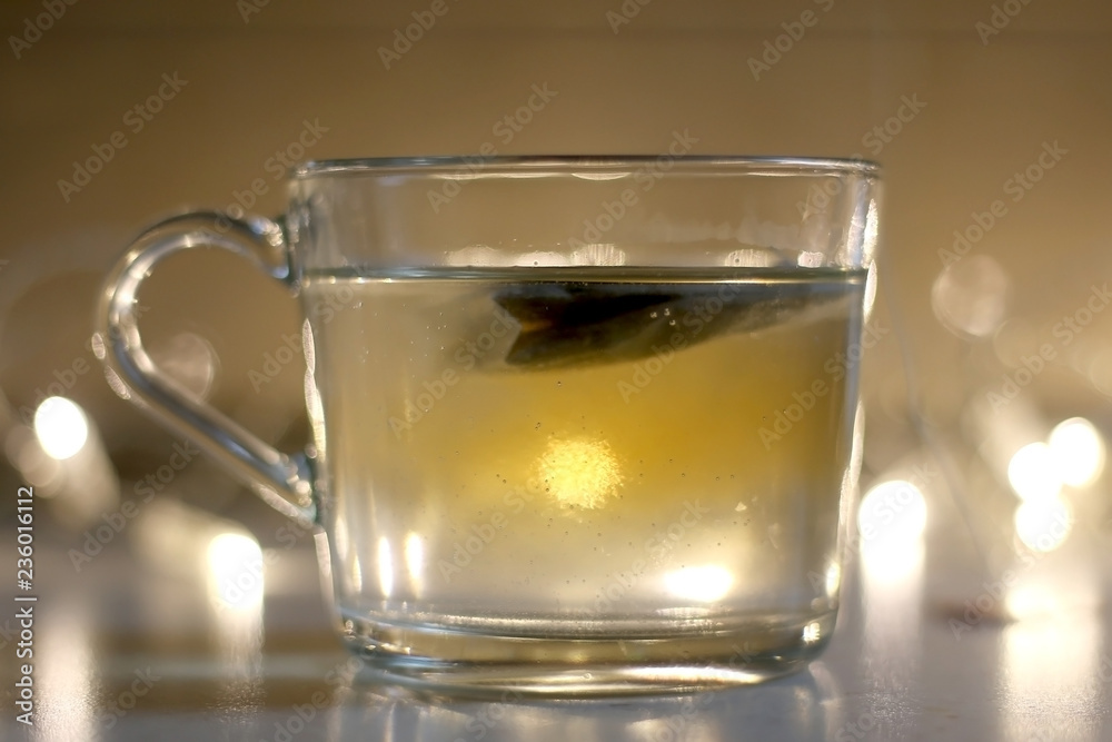 Cup of tea with slice of orange. Selective focus, fairy lights in the background. Cup of tea with slice of orange. Selective focus, fairy lights in the background.