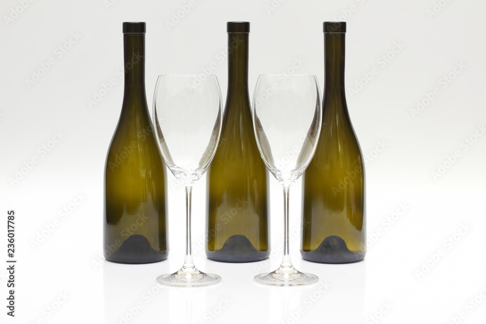 Three empty upturned wine bottles and two glasses on a white background