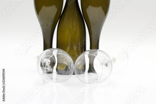 Three empty wine bottles and two glasses close up on a white background