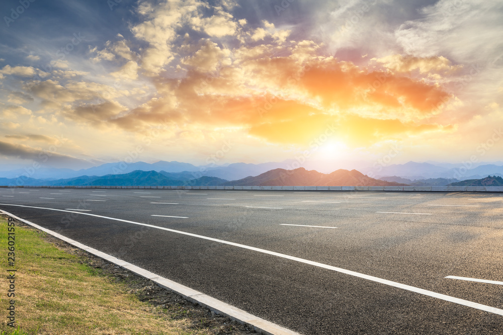 Asphalt road and mountains at beautiful sunset