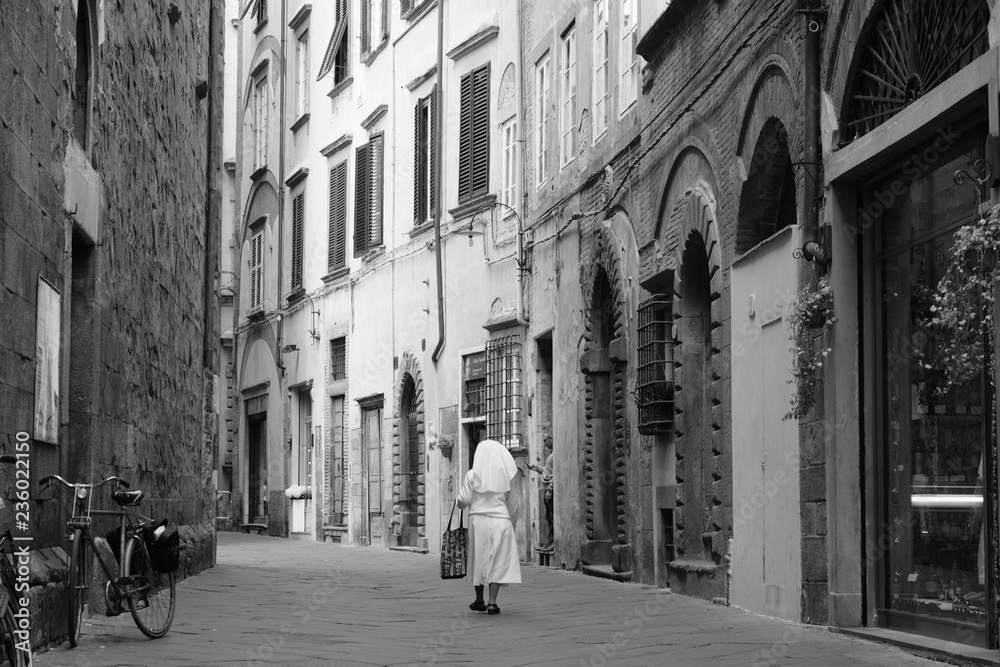 Nun walking down empty street in Italian village in the Tuscan region