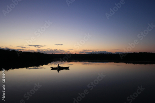 Kayaker in silhouette on a perfectly calm West Lake at first light in Everglades National Park, Florida.