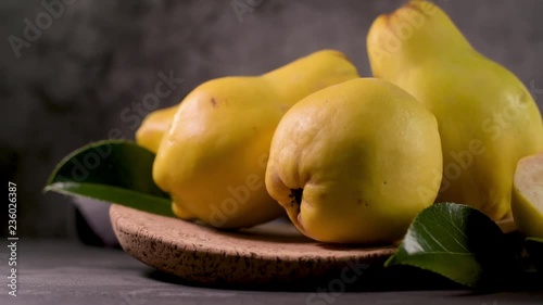 Ripe yellow quinces or queen apple fruits and sliced quince halves with seeds in craft cork plates on black rustic background.