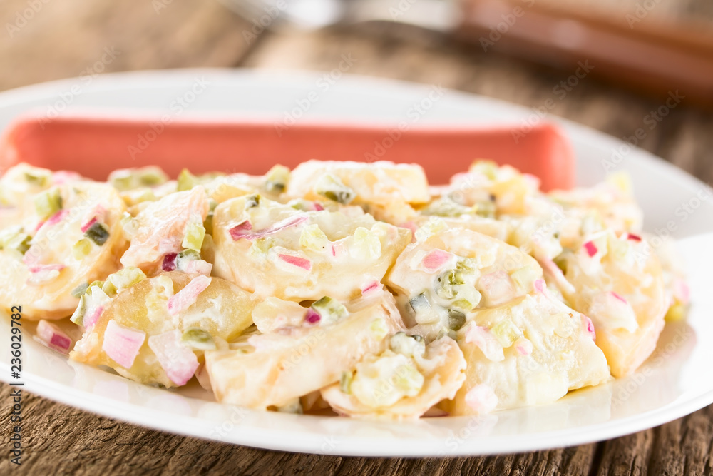 Fresh homemade German Kartoffelsalat potato salad made of potato, onion, pickle and mayonnaise, served with sausage, traditional Christmas Eve dinner (Selective Focus in the middle of the image) Fresh homemade German Kartoffelsalat potato salad made of potato, onion, pickle and mayonnaise, served with sausage, traditional Christmas Eve dinner (Selective Focus in the middle of the image)