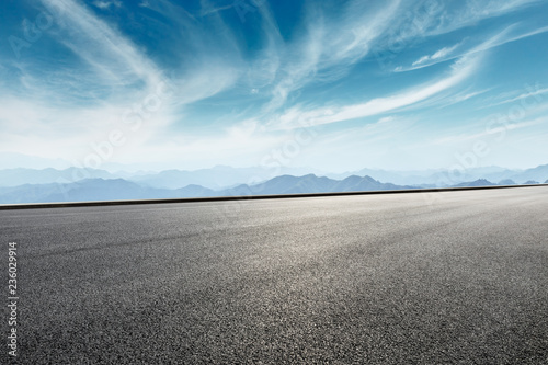 Asphalt road and mountains with white clouds © ABCDstock