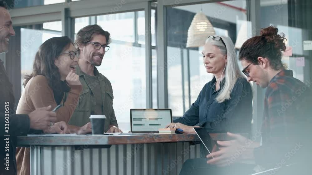 Business team discussing working during meeting and smiling. Group of happy business people having casual talk during meeting.