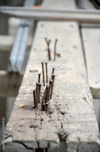 A close up image of rusty nails on a wooden bar in a modern house construction site.