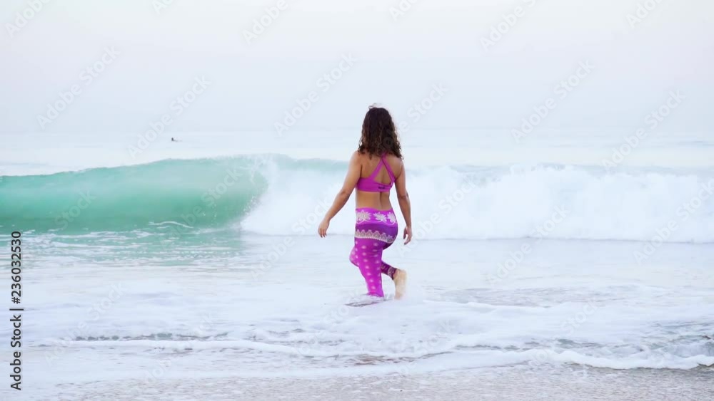woman walking into ocean bending down washing herself woman walking into ocean bending down washing herself