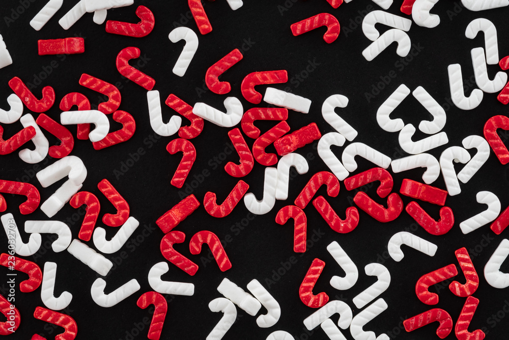 Red and white candy cane sprinkles scattered on a black background Red and white candy cane sprinkles scattered on a black background