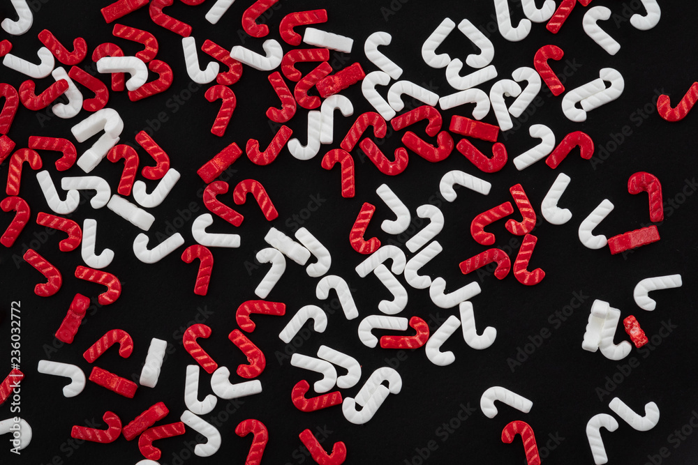 Red and white candy cane sprinkles scattered on a black background Red and white candy cane sprinkles scattered on a black background