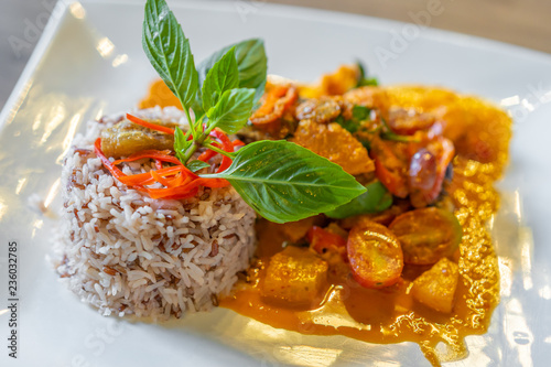 duck confit with red curry served with brown rice on plate photo