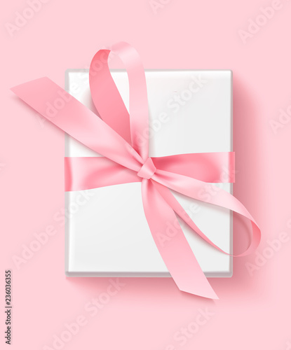 Decorative white gift box with pink bow isolated on pink background for Mother's day design. Top view.