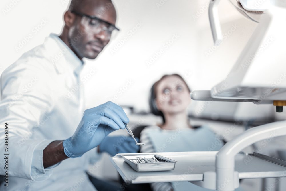 Obraz premium Attentive stomatologist taking instrument in right hand