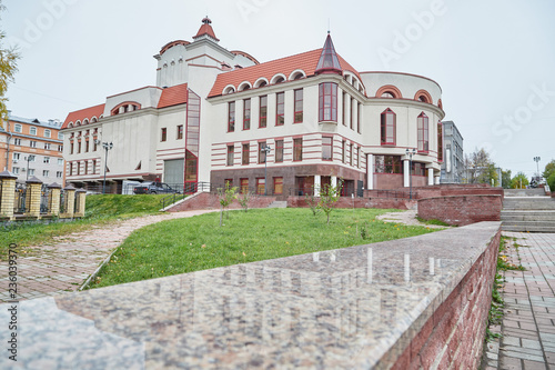 Vintage beautiful building in grey and red colours and turrets on the roof with cloudy sky background. Puppet theatre in Kirov