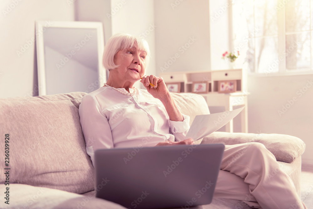 Neat short-haired senior thinking about her painting Neat short-haired senior thinking about her painting