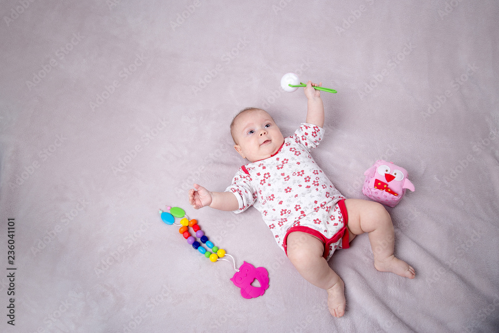 Naklejka premium Baby girl smiling around baby toys