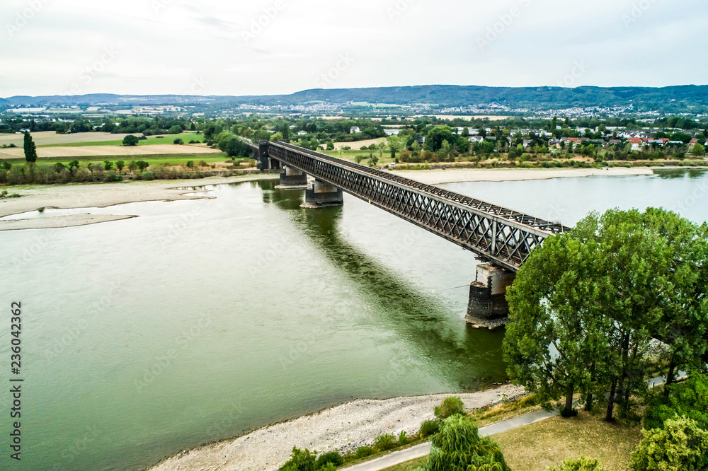 old train bridge near koblenz during Drought Germany, low water Rhine river influending water transport freight ships
