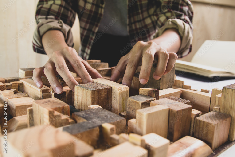 Concept architects, Man architect Hands making checking the project wood model. equipment architects On the desk with a blueprint in the office Concept architects, Man architect Hands making checking the project wood model. equipment architects On the desk with a blueprint in the office