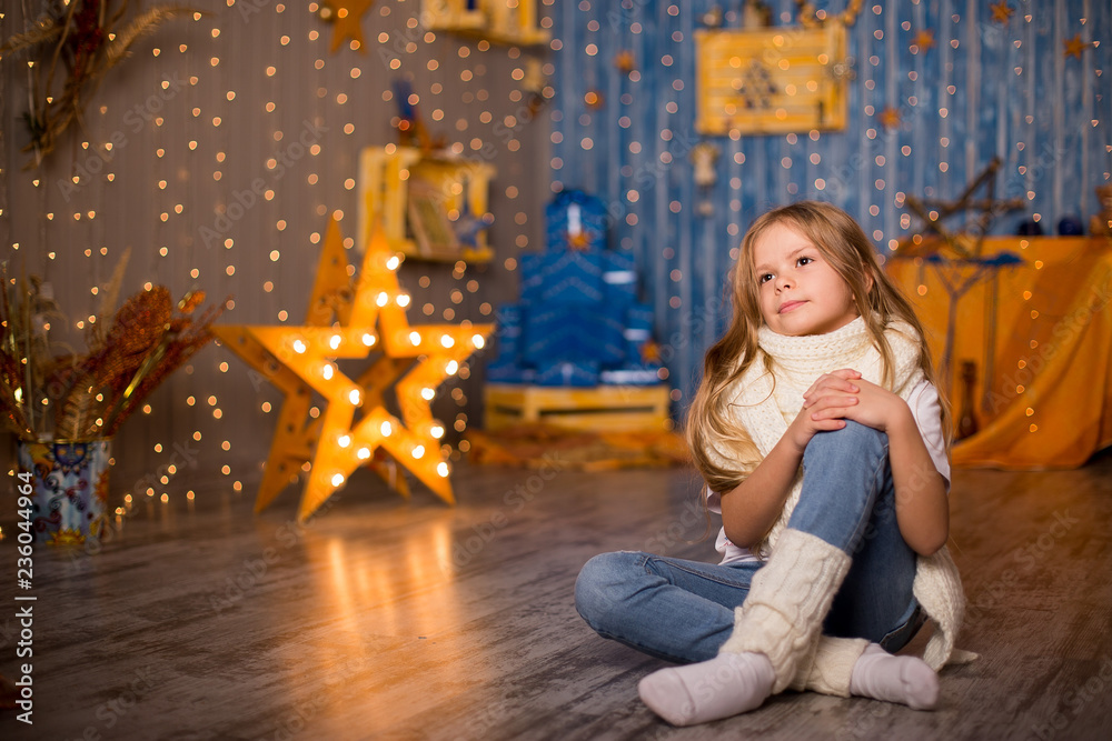 A girl dreams of gifts on a Christmas background of bright lights from the garland. A girl dreams of gifts on a Christmas background of bright lights from the garland.