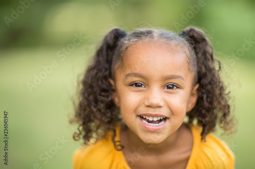 Cute mixed race little girl laughing and smiling.