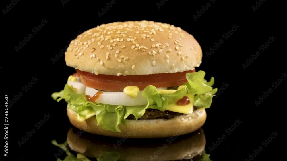 Rotation of delicious burger over black background. Rotation of delicious burger over black background.