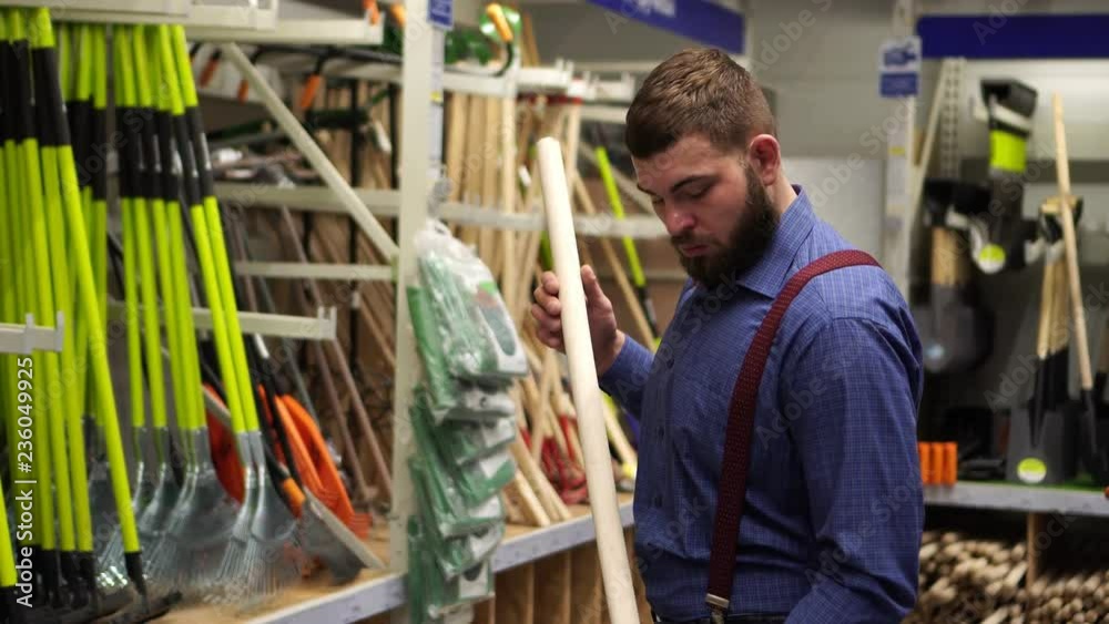 Male buyer in the hardware store chooses a shovel. Male buyer in the hardware store chooses a shovel.