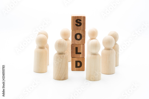 Wooden figures as business team in circle around word SOLD