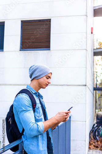 Outdoor portrait of modern young man with mobile phone in the street.
