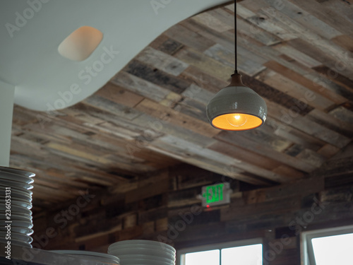 Wooden roof of trendy restaurant with hanging lights and stack of ceramic plates