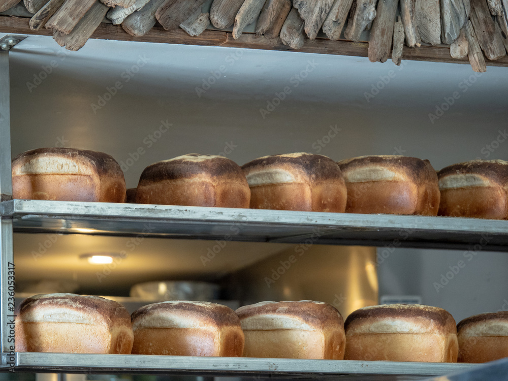 Various loafs of freshly baked bread sitting on steel kitchen shelf ready for serving