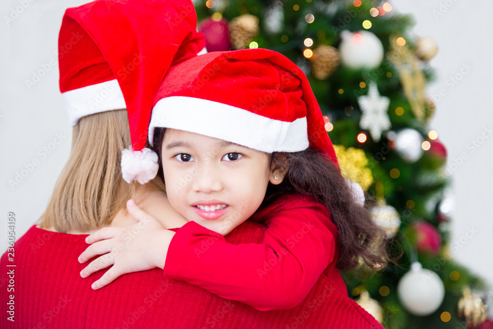 Mother and her daughter wearing christmas costume and smiling in room with Christmas tree decoration Mother and her daughter wearing christmas costume and smiling in room with Christmas tree decoration
