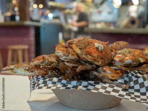 Steamed Chesapeake Bay blue crabs covered in seasoning sitting in paper bowl on paper covered table cloth