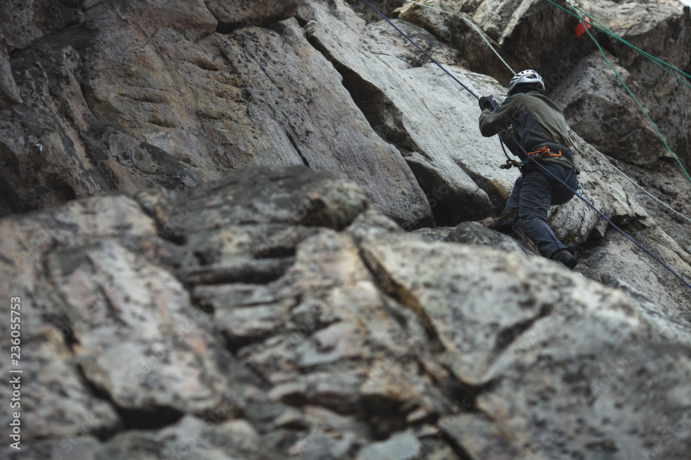 Climber pulls on the rock wall on a safety rope during competitions in sport climbing. Climber pulls on the rock wall on a safety rope during competitions in sport climbing.
