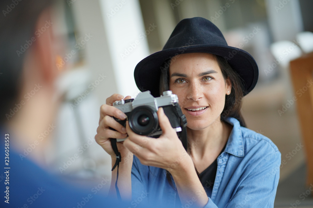   Trendy stunning brunette taking photos of model with vintage camera