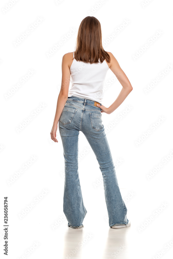 Back view of young pretty woman posing in bell bottom jeans on white  background foto de Stock | Adobe Stock
