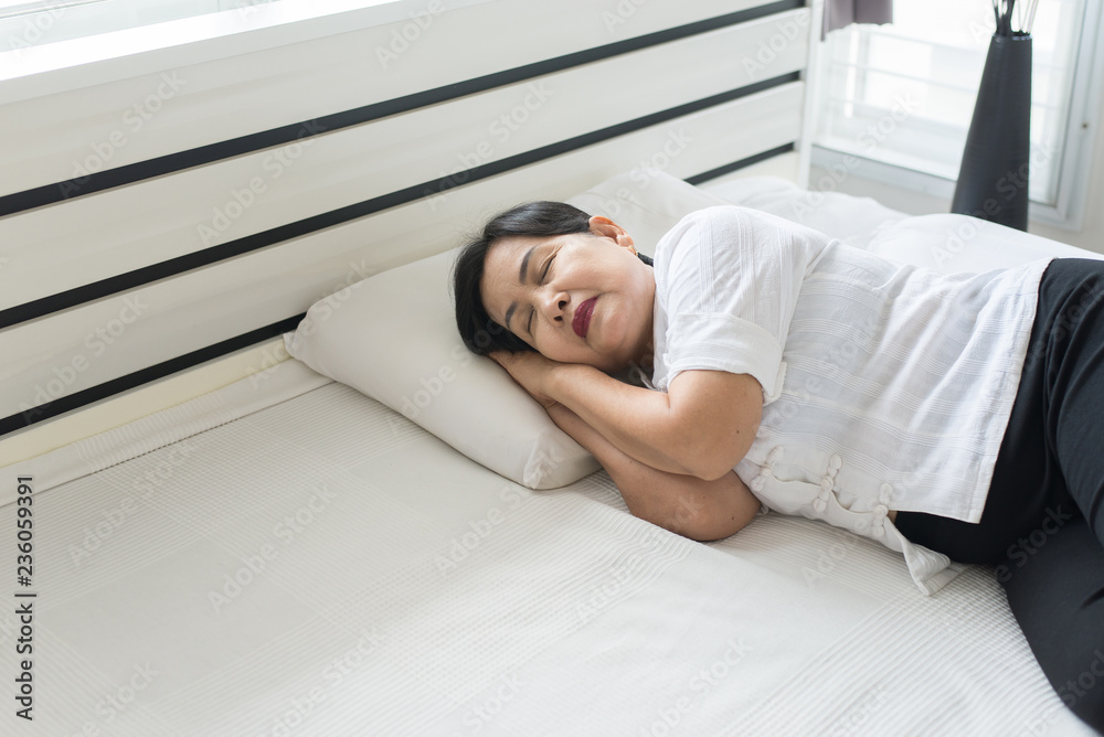 Asian elderly woman sleeping happy on bed and smiling her hands beside her head,Good dream,Daydream Asian elderly woman sleeping happy on bed and smiling her hands beside her head,Good dream,Daydream