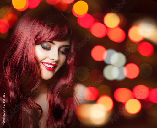Cheerful redhead woman with long red curly hairstyle on bright color party bokeh glitter background