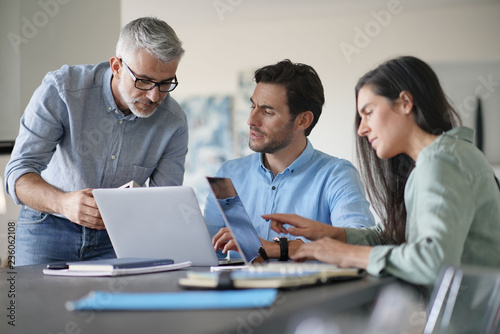  Young colleagues with older boss working with computers photo