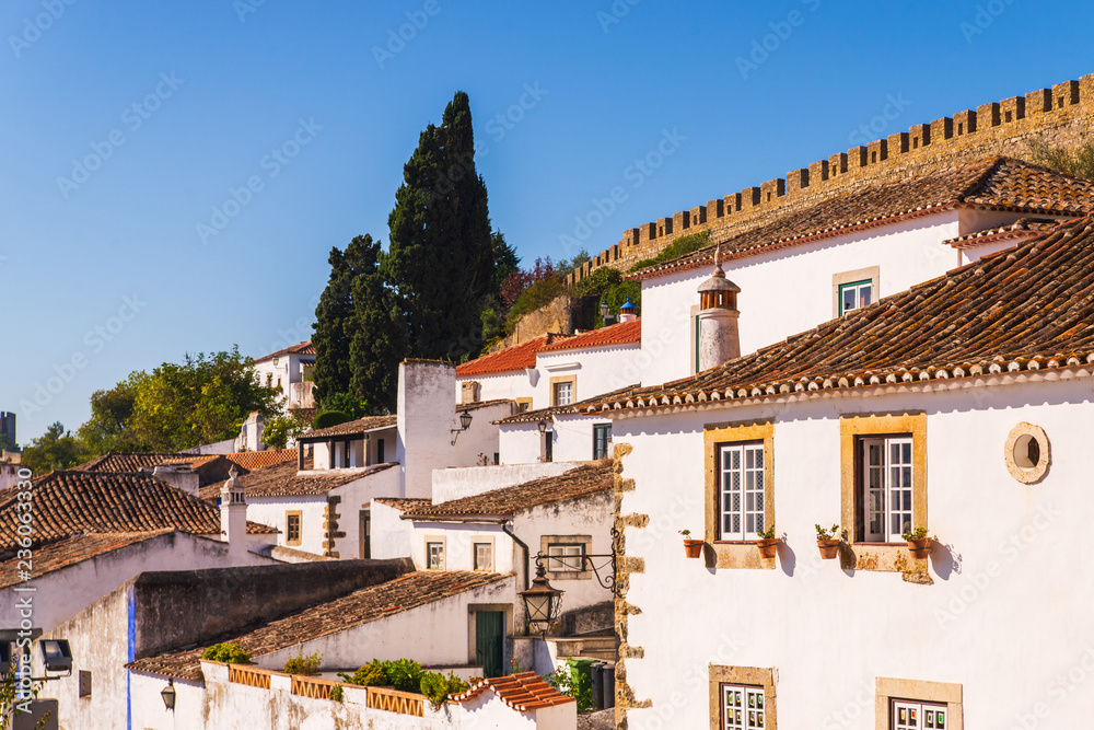 Traditional architecture of old european town. Narrow street of the ancient town. Scenic old town with medieval architecture. Popular tourist destination. White houses and red tiled roofs.