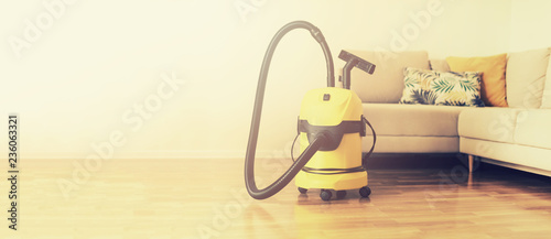 Cleaning service concept. Banner. Yellow vacuum cleaner, sofa on light background with copy space