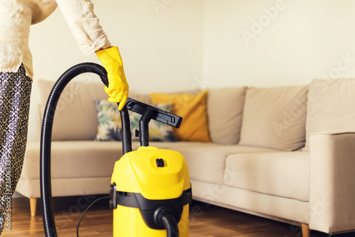 Woman cleaning sofa with yellow vacuum cleaner. Copy space. Cleaning service concept