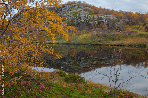 Autumn landscape. The rocks and the sky are reflected in the lake. © Moroshka