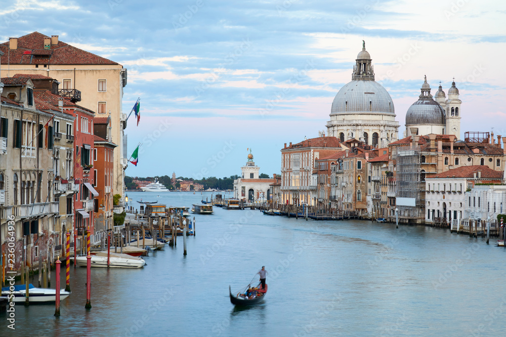 Grand Canal in Venice with gondola and Saint Mary of Health basilica at dusk in Italy