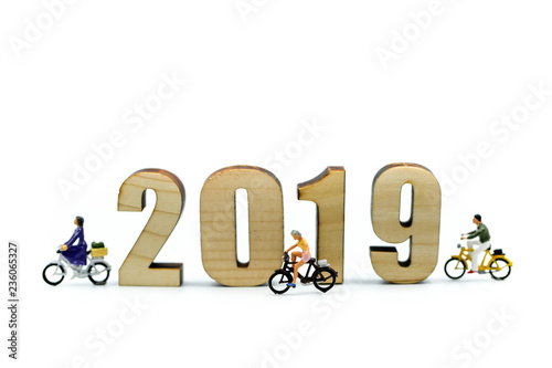 Miniature people : man and friend ride bicycle with wooden number of 2019,Happy New Year 2019 concept.